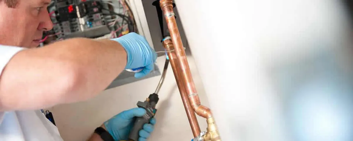 Water heater repair technician testing copper pipe connections and controls in Long Beach, CA
